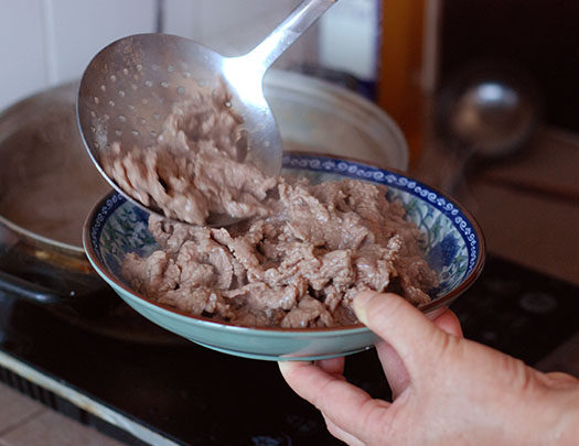 牛肉涮米酒,药五分钟后,捞出牛肉装盘,并倒入捣好的葱姜泥拌匀即可。