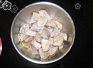 梅菜芋香红烧肉,煮肉的同时,在干净的锅中注入足够的油,用中火加热至5成熟,放入芋头块油炸至出现金边捞出控干放入大碗的底部