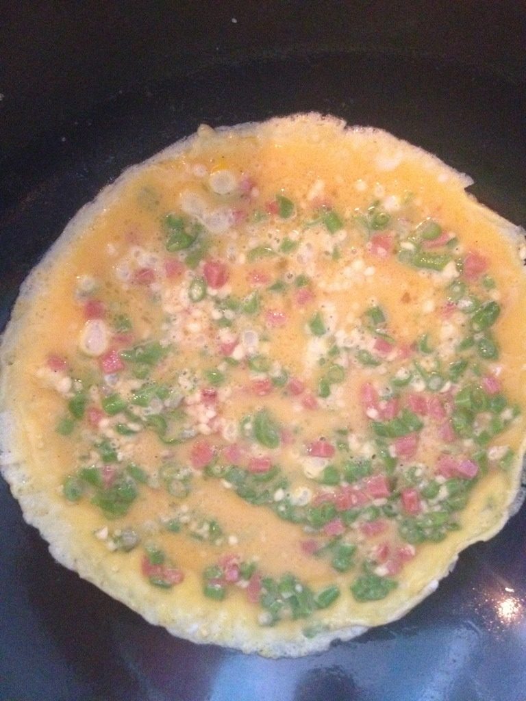 豆角煎蛋饼,将火腿和豆角一起放入拌匀，锅内加油预热，将蛋液混合液倒入，用铲推平一面煎黄后翻面煎熟另一面