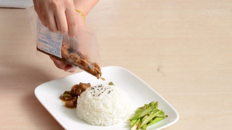 红烧鸡腿盖浇饭,加热好的料包取出剪开倒在米饭上,米饭上点缀适量黑芝麻
