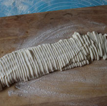 荆芥肉丝手擀面 ,面先擀成圆形，撒上面粉防粘，然后重复叠起来，切成面条