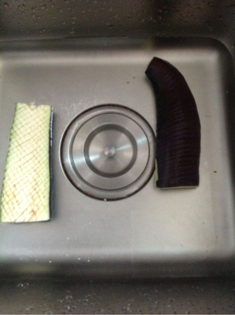 蒜茸烤茄子,如图,水池或大盆里放适量水,加一勺盐,将划好的茄子泡入水中20分钟