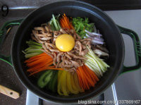 铸铁锅版石锅拌饭,码上各色蔬菜,鸡肉丝一半放在边上,一半放在中间,在鸡肉上打一个生鸡蛋;