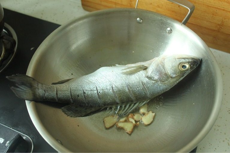 酱闷彩椒鲈鱼,2、锅中烧热油至七成热,将鲈鱼擦干水分,放入锅中煎至两面发黄。