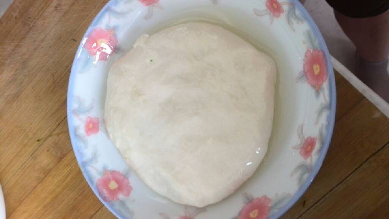 猪肉茴香馅饼,等面醒好后,手沾油揪出一个小面团放入涂好油的盘子当中,摊薄把馅包进去。