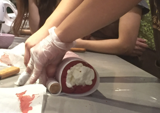 红丝绒蛋糕卷,卷蛋糕卷时,利用擀面杖提起油纸往蛋糕中间先压紧,然后擀面杖提到蛋糕卷的前面,一边提最下面的油纸一边用擀面杖向前卷压,最后把油纸拉紧