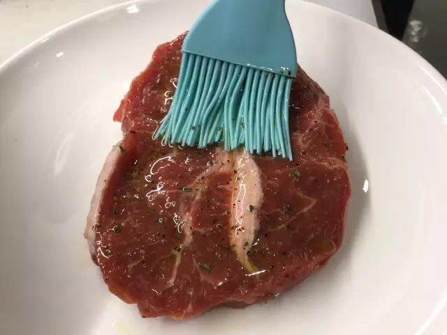 香煎牛扒配红酒汁,将香料油均匀地扫在牛扒上,要小心,不要让香料叶子留在牛肉上。静置腌制30min即可