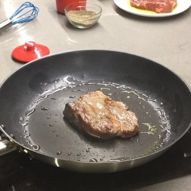 香煎牛扒配红酒汁,先煎香一面,观察牛扒的侧面,待颜色爬升至2mm左右,牛扒表面开始渗出血水即可翻面。两面各煎30秒