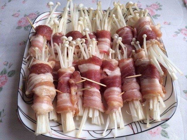 五花肉金针菇卷,摆盘前把盐放入五花肉,金针菇拌匀,用五花肉卷住适量的金针菇,再用牙签固定好