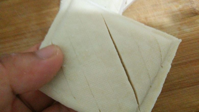 卤豆干,在白<a style='color:red;display:inline-block;' href='/shicai/ 5879'>豆干</a>的正面用刀斜着划出一些长口,注意不要切断。
