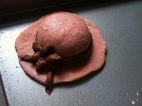 粉嫩帽子面包,可可面团剩余部分搓成细长条,围在上一步圆面团周围,将小花点缀上去,完成帽子造型。