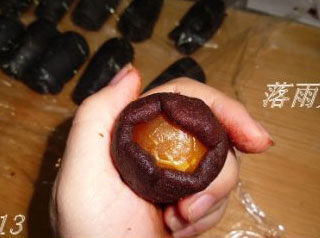 竹炭蛋黄酥月饼,取一块豆沙压扁,放上咸蛋黄,包成圆球
