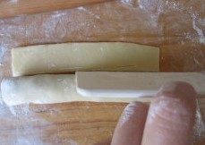 口感不俗的“黄金豆沙一口酥”,用面片将枣泥馅包裹起来,成为一个长的圆柱形长条,再切去多余的边;