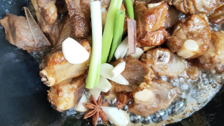 排骨土豆炖豆角,将排骨翻炒至金黄色,加入葱姜蒜,再加入花椒大料翻炒。