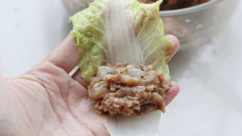 白菜卷肉,将菜叶铺平,取适量虾肉馅放在前端。