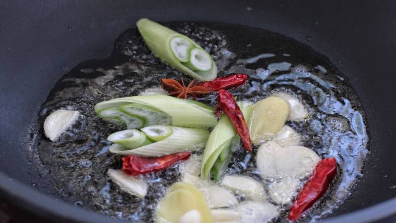 红烧翅根,锅中倒适量食用油烧至五成热,下入葱姜蒜、八角和红干椒,小火炒出香味,注意别把红干椒炒黑了。