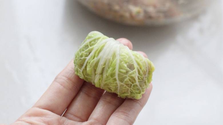 白菜卷肉,慢慢向上卷起,到叶片位置时把两边也包裹住直至卷完。
