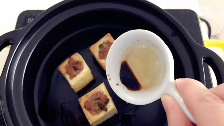 宝宝辅食:豆腐箱(肉末酿豆腐),煎好的豆腐块转移至砂锅中,加入少许宝宝酱油、少许盐。