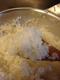 剩饭做米糕,用勺子搅拌米饭,使其均匀受热并能吸收到水分,直到每粒米看起来都吸饱水很柔软的状态。