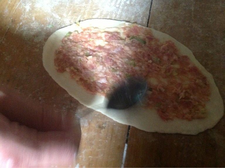 家常夹肉烧饼,如图将剂子擀成长条状,抹上调好的肉馅。