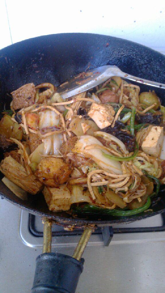 周君记版麻辣香锅,料融化好后,先在锅里放入荤菜,翻炒使其入味,然后再放入准备好的所有素菜,翻炒均匀。