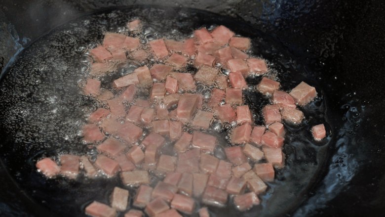 青豆火腿烩豆腐,锅中油热后放入火腿丁炒香加青豆，炒片刻加少许水焖煮。