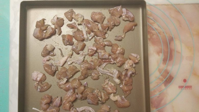 黑椒鸡肉披萨,趁着发酵的时间,做好其它准备工作。首先把腌制好的鸡腿肉平铺在烤盘上。