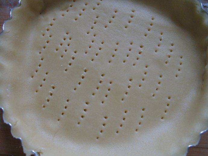 核桃塔,派皮擀成饼状放入模具中铺平，并用擀面杖将多余派皮去除，用叉子在派皮上叉出小孔