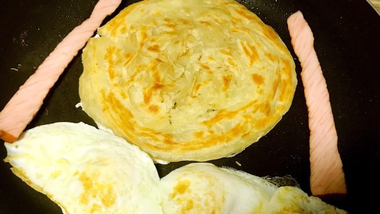 里脊蛋手抓饼,再次翻面,鸡蛋定型后也翻面煎熟,里脊肠也可以放在锅内一起加热。