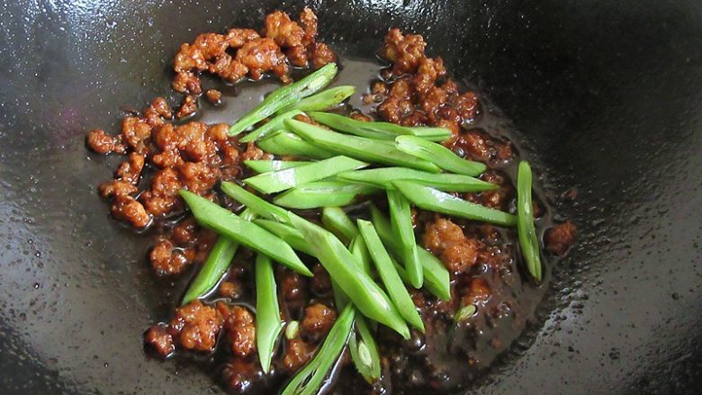 肉末酱香豆角面,倒入宽豆角干炒片刻，豆角入味上色熟透即可，注意豆角一定要炒熟，半生吃容易腹泻