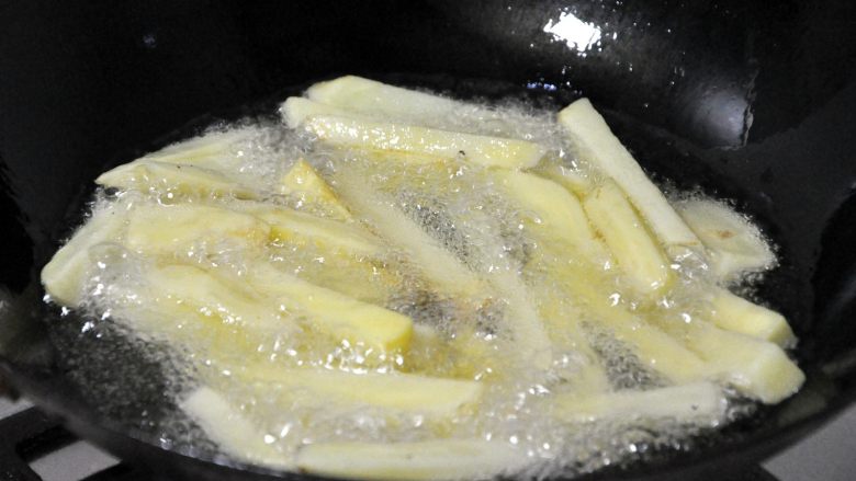 香辣干锅兔,锅中热油,倒入控干水份的土豆条,炸至金黄色。