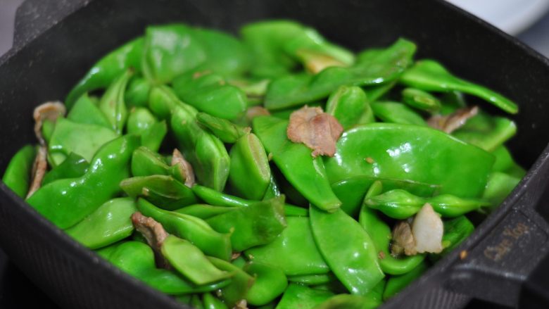 五花肉炖油豆角,再继续翻炒,锅内倒入没过豆角1/2的水量(要加开水),盖上锅盖小火炖15分钟左右。