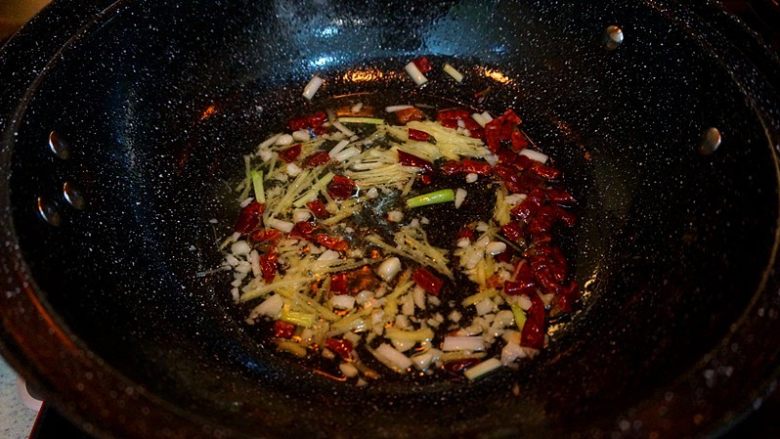家常烧鲫鱼,锅底留油,放入少许干辣椒,生姜丝儿,大蒜末,葱白段