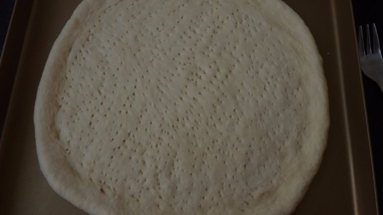 不用装就很嫩~黑椒羊肉披萨,把面团擀开放在烤盘内,用叉子扎上小孔