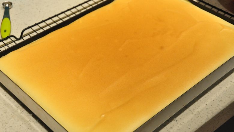 日式豆乳盒子蛋糕,烘烤结束后,取出烤盘,让烤盘从20厘米的高处摔到操作台上,震出热气。