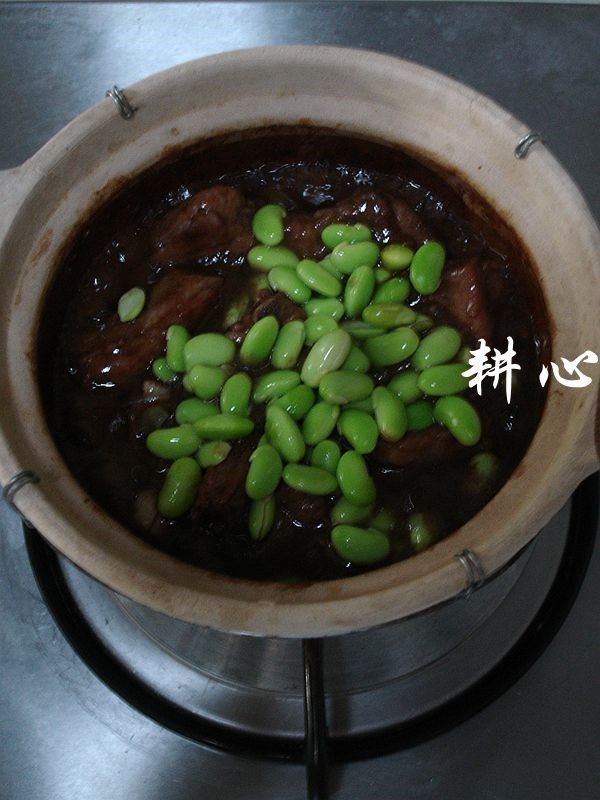 虾酱排骨粉丝煲,揭盖,放入毛豆。
