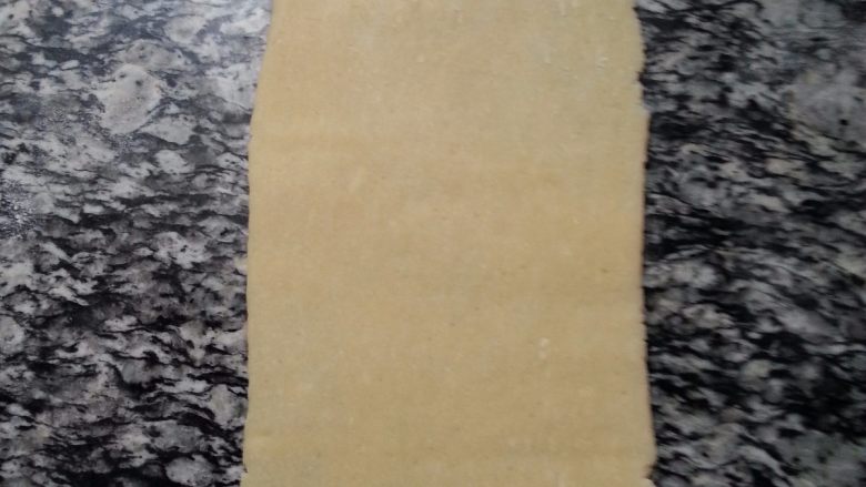 肉桂苹果派,将松驰后的派皮取出,将两端向中间折3折,接着擀成薄片,再重复此动用一次,接着分成2分,分别擀成厚度为0.3CM的薄片,其中1份切成长21CM