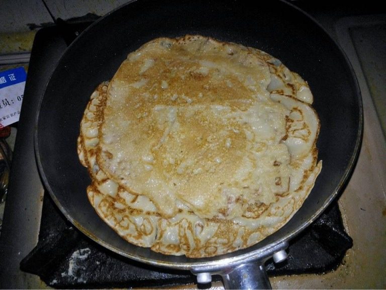 香蕉牛奶饼,煎锅倒入适量食用油烧热，倒入一部分搅拌均匀的面粉（不需要太多，可煎多个香蕉牛奶饼），晃动煎锅使面粉均匀的铺在煎锅里