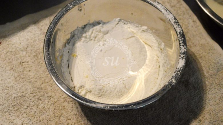 一个完美的戚风蛋糕是怎样炼成的,另外一半低筋面粉过筛加入蛋黄液中,手持打蛋器混合均匀。这里注意要使用“之”字形手法,避免面粉起筋