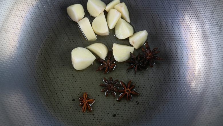 土豆萝卜焖牛腩,准备一个炒锅,倒入适量的油,加入大蒜、八角,小火煸炒。