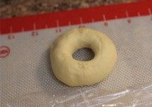 原味甜甜圈,用两只手指将洞撑开,放置在剪好的油纸上