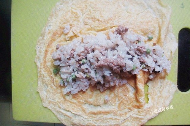 蛋皮包饭,把一份炒好的饭放在蛋皮中央,把蛋皮的两边翻起,向中间褶,把饭包起來。