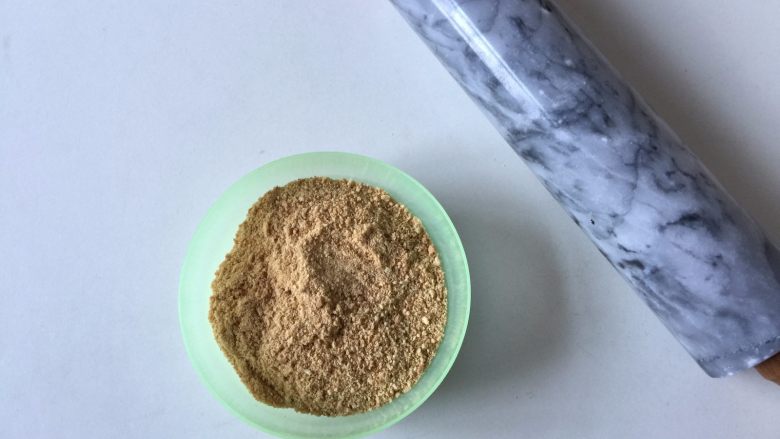 百香果冻芝士蛋糕,将消化饼干放保鲜袋中,用擀面杖碾碎至小颗粒