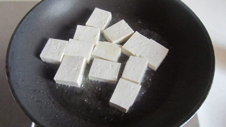 雪菜肉末烧豆腐,烧热锅,放少许油, 将切成小块的豆腐下去煎;