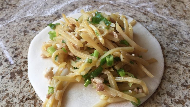 不用发面的土豆丝肉饼,每一个小剂子,揉成光滑的面团,然后擀成圆,上面放上事先炒好的土豆丝;