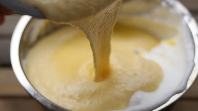 杏仁乳酪蛋糕,把翻拌好的蛋黄糊倒入剩下的蛋清中继续翻拌。