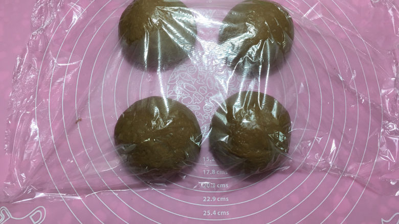 可可味蔓越梅奶酪包,取出面团进行排气,排气后将面团平均分成四份,盖保鲜膜醒面15分钟。