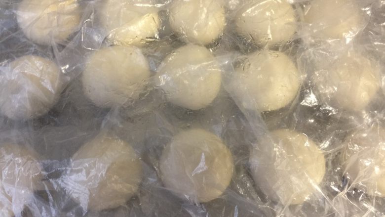 美味肉松酥,将一个油皮用手按扁,包入一个油酥,收好收口滚圆,依次完成所有,操作的时候将面团都盖上保鲜膜。