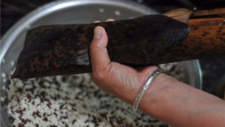 鲜掉眉毛的湘西特色美食——笋壳腊肉棕,叶片两边往上盖,将糯米包起来,再将两端包裹好