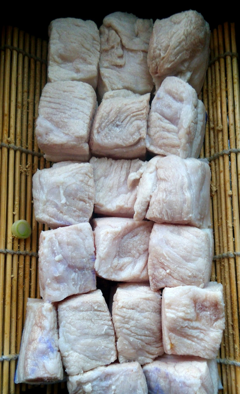 家常东坡肉,大砂锅里用竹箅子垫底,先铺上葱和姜,再将猪五花的皮面朝下,排在上面